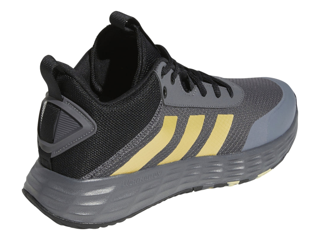 Tenis Adidas OwnTheGame 2.0 en color gris y negro con tres franjas doradas laterales.