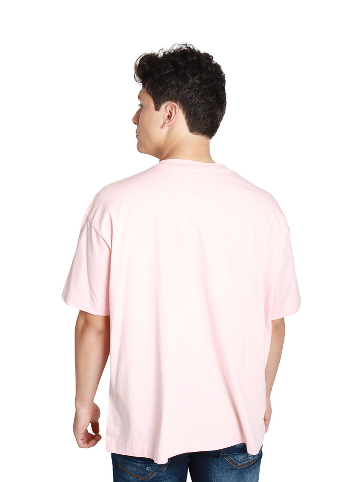 Hombre vistiendo camiseta rosa claro Calvin Klein con logotipo amarillo frontal.