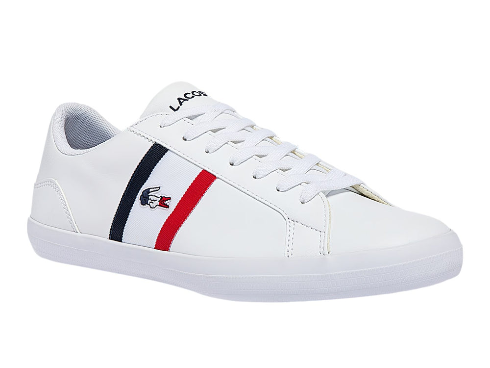 Tenis blancos Lacoste de corte bajo con franjas azul marino y rojo en el lateral y logotipo del cocodrilo.