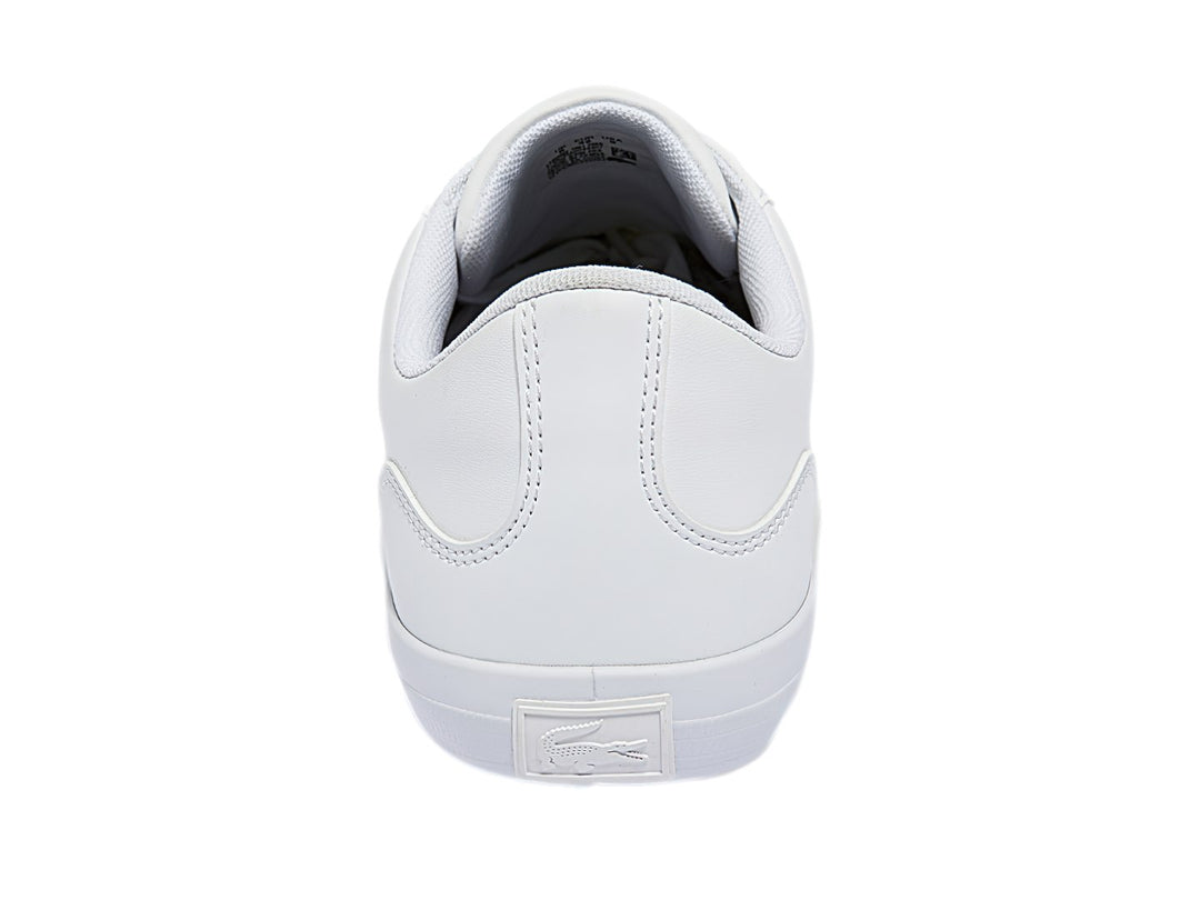 Tenis blancos Lacoste de corte bajo con franjas azul marino y rojo en el lateral y logotipo del cocodrilo.