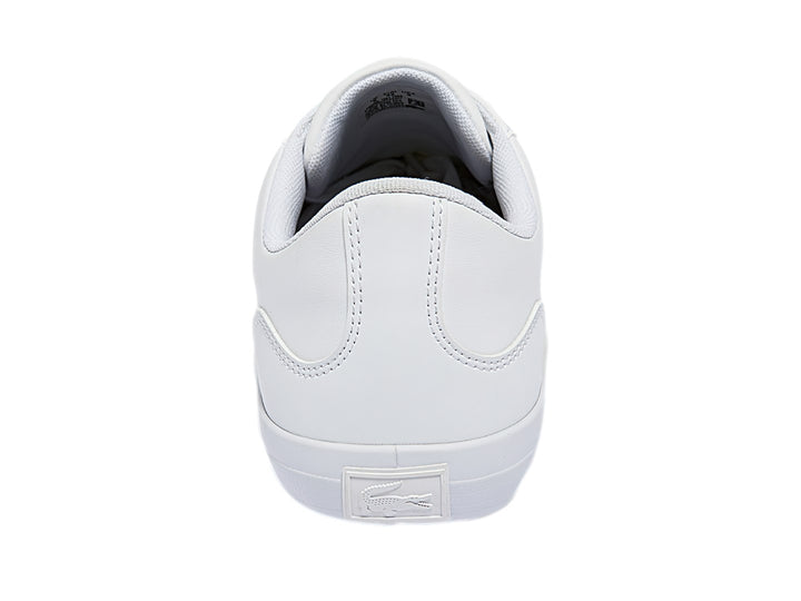 Tenis blancos Lacoste de corte bajo con franjas azul marino y rojo en el lateral y logotipo del cocodrilo.