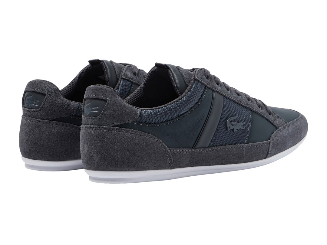 Tenis Lacoste color gris con suela blanca, detalles en gamuza y tela.