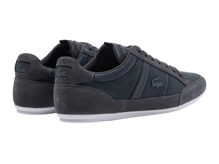 Tenis Lacoste color gris con suela blanca, detalles en gamuza y tela.