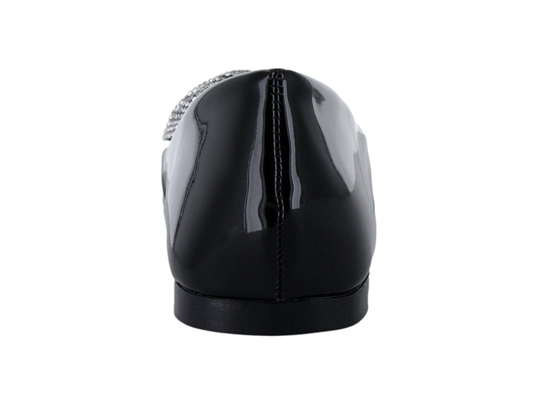 Zapato plano de charol negro con un moño decorativo de brillantes en la parte frontal.
