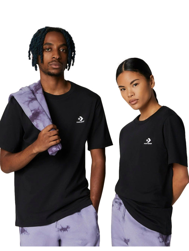 Dos modelos vistiendo una camiseta negra de manga corta con logo de Converse en el pecho.