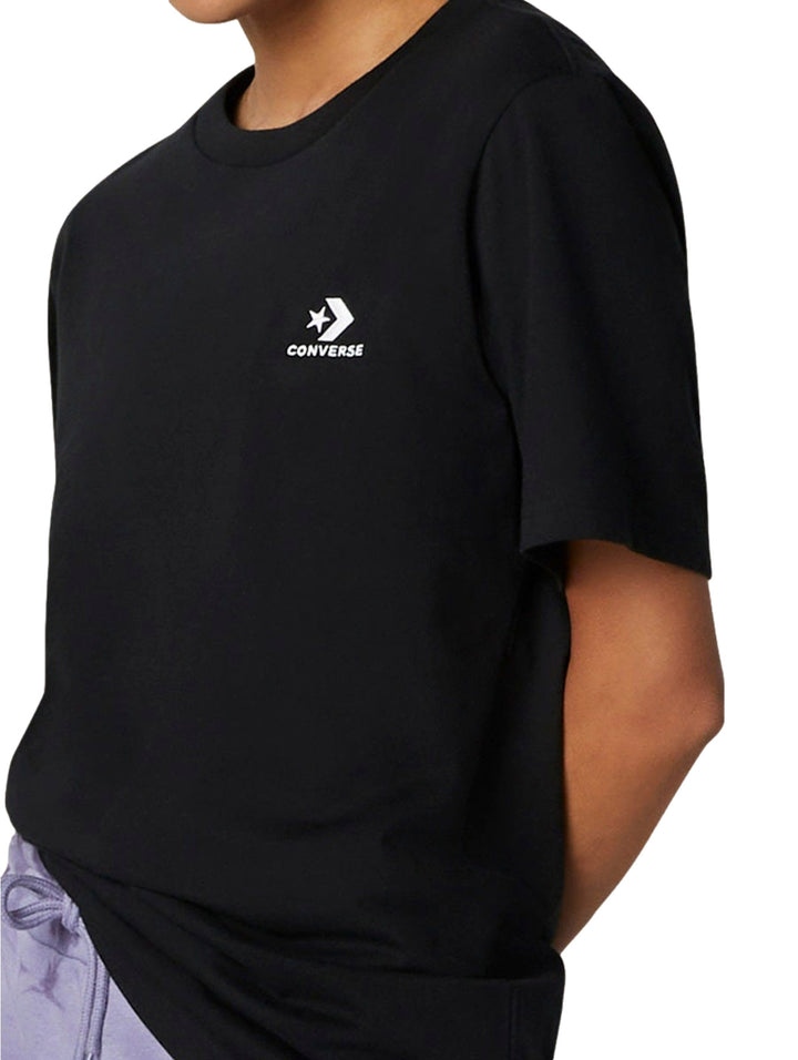 Dos modelos vistiendo una camiseta negra de manga corta con logo de Converse en el pecho.