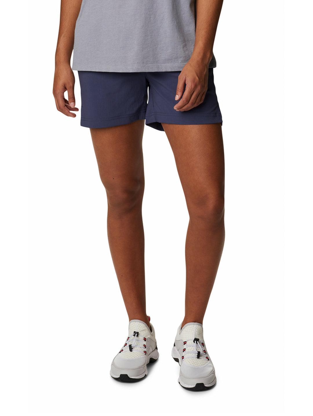 Persona vistiendo shorts deportivos color azul marino de la marca Columbia y tenis blancos.