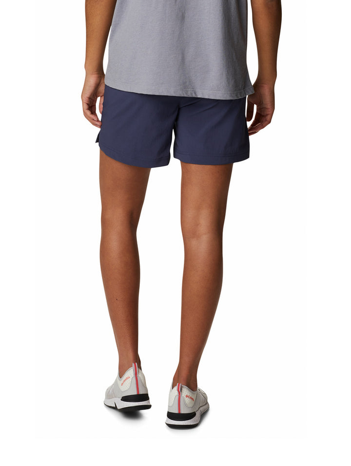 Persona vistiendo shorts deportivos color azul marino de la marca Columbia y tenis blancos.