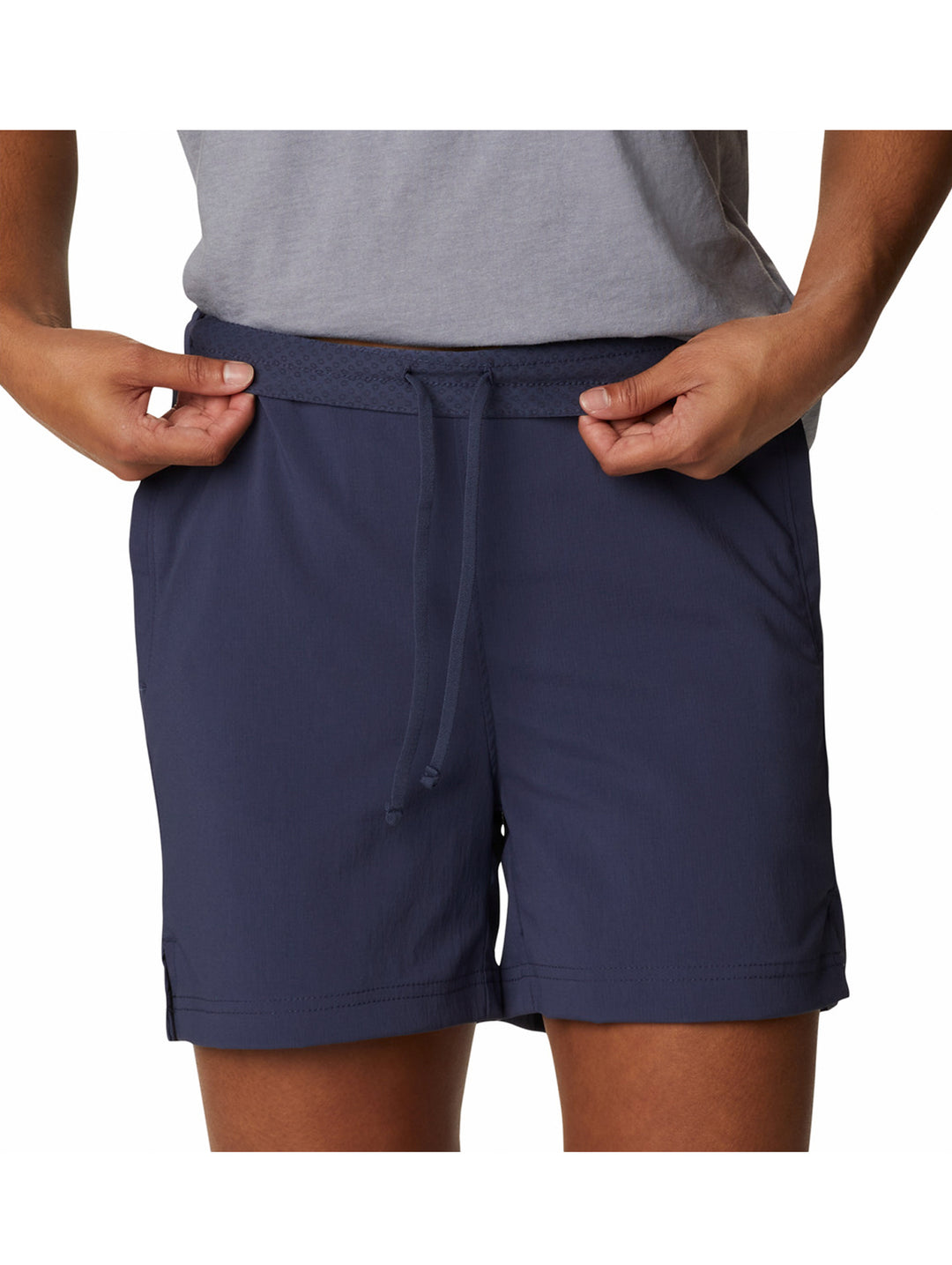 Persona vistiendo shorts deportivos color azul marino de la marca Columbia y tenis blancos.