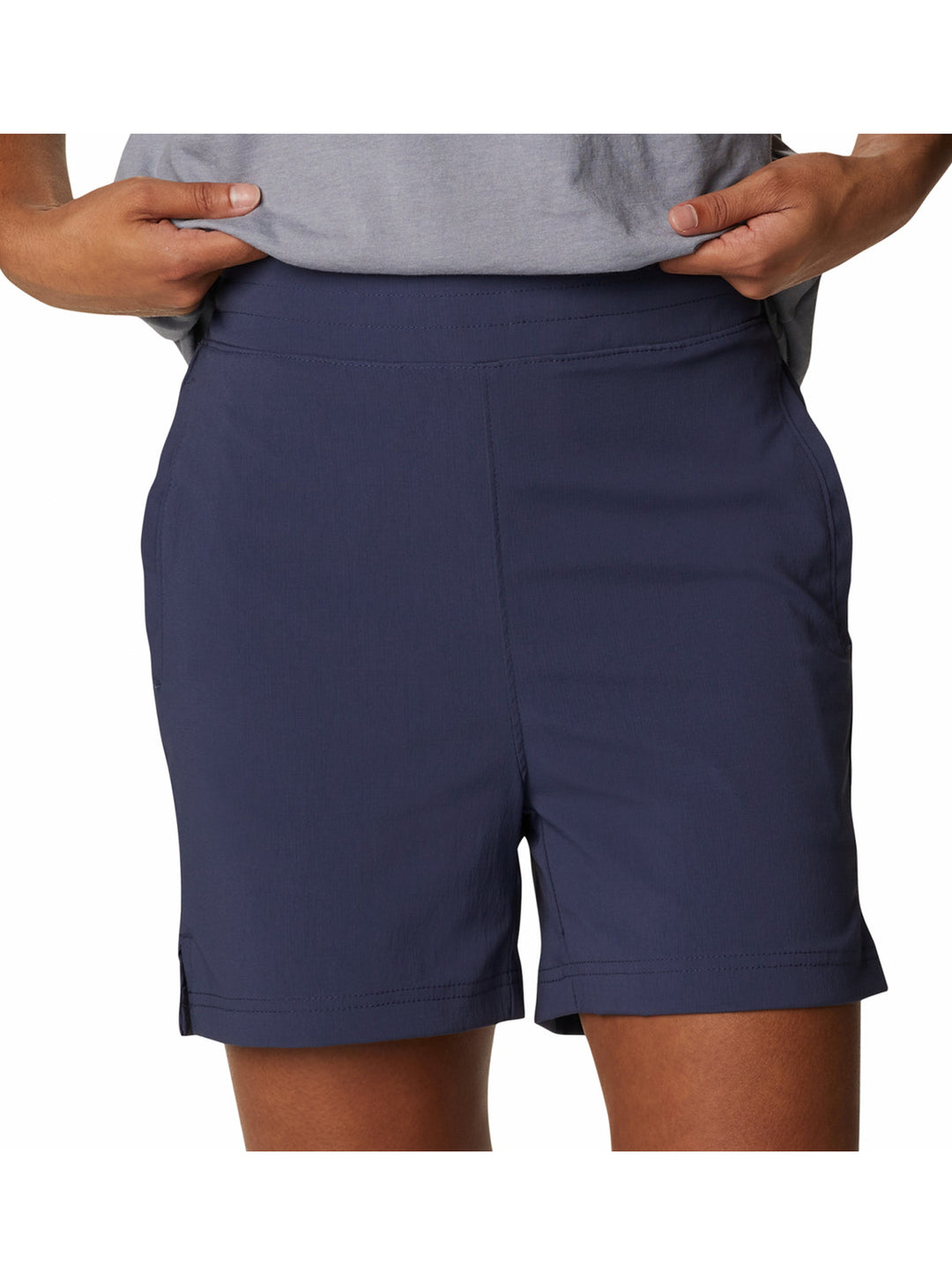 Persona vistiendo shorts deportivos color azul marino de la marca Columbia y tenis blancos.