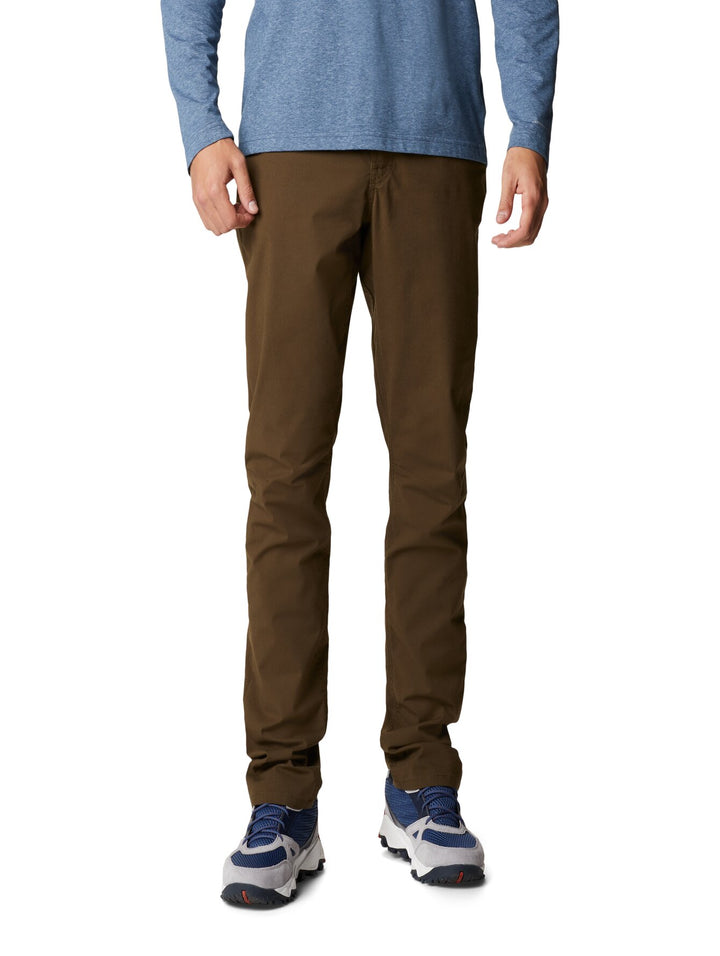 Hombre vistiendo pantalones Columbia color verde oliva, camiseta azul y calzado deportivo.