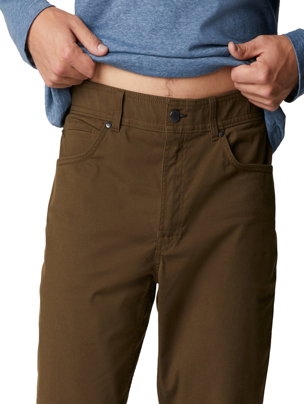 Hombre vistiendo pantalones Columbia color verde oliva, camiseta azul y calzado deportivo.