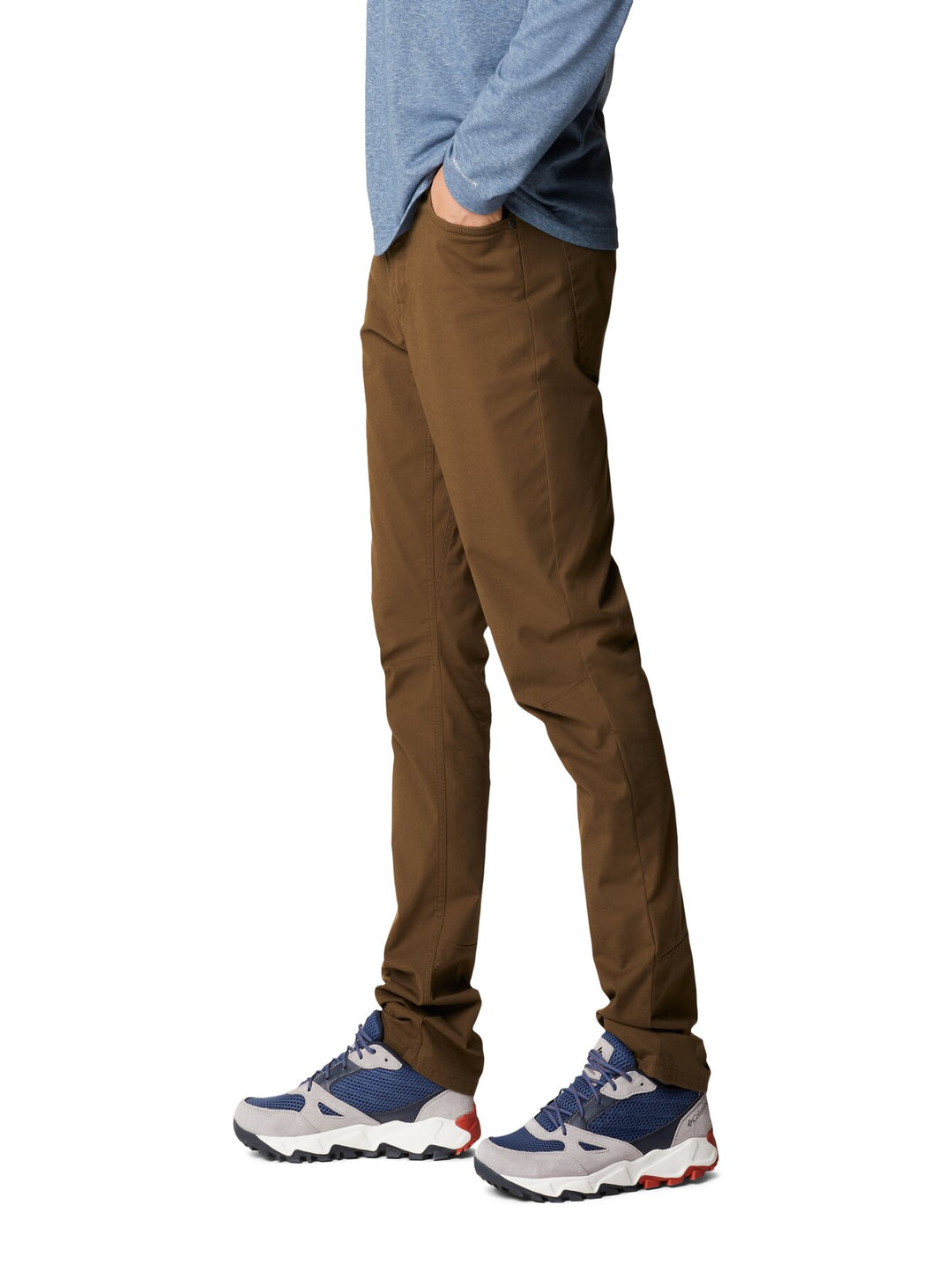 Hombre vistiendo pantalones Columbia color verde oliva, camiseta azul y calzado deportivo.
