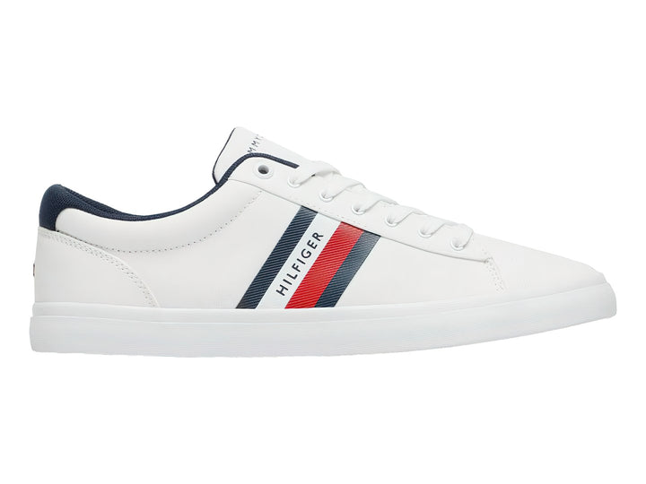 Tenis Tommy Hilfiger color blanco con franjas azul y roja en el lateral y suela blanca.