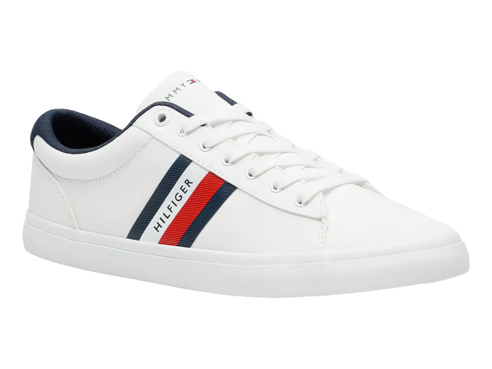 Tenis Tommy Hilfiger color blanco con franjas azul y roja en el lateral y suela blanca.