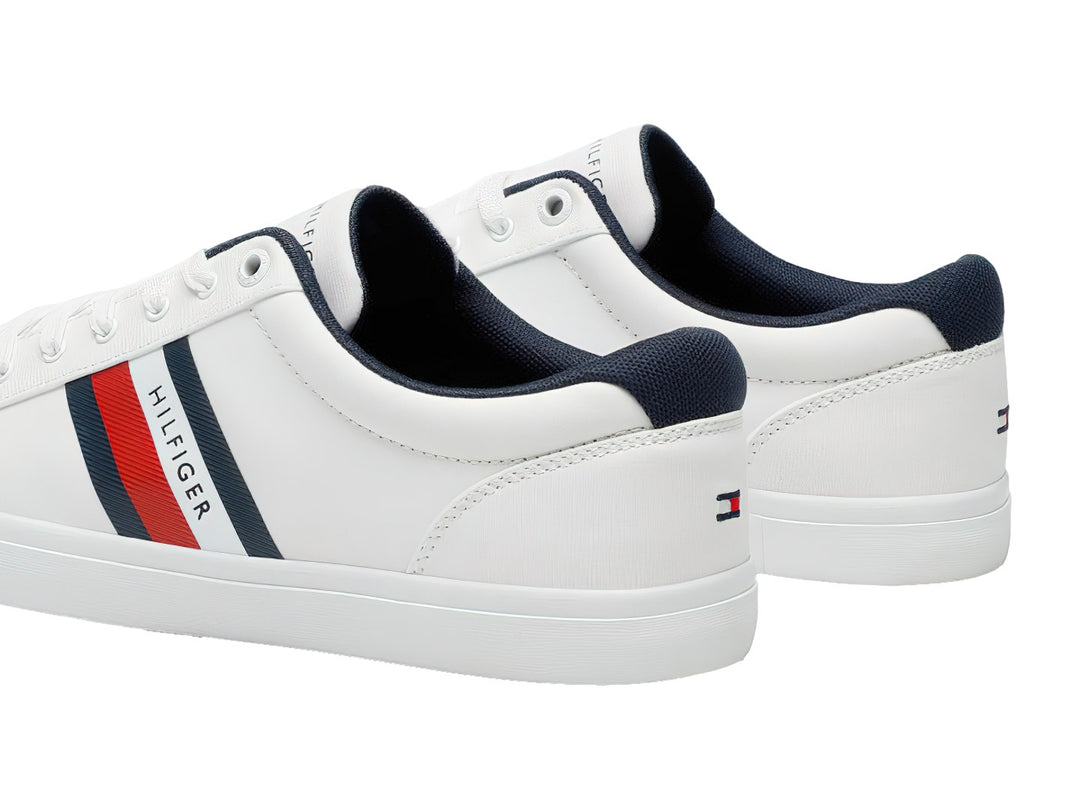 Tenis Tommy Hilfiger color blanco con franjas azul y roja en el lateral y suela blanca.