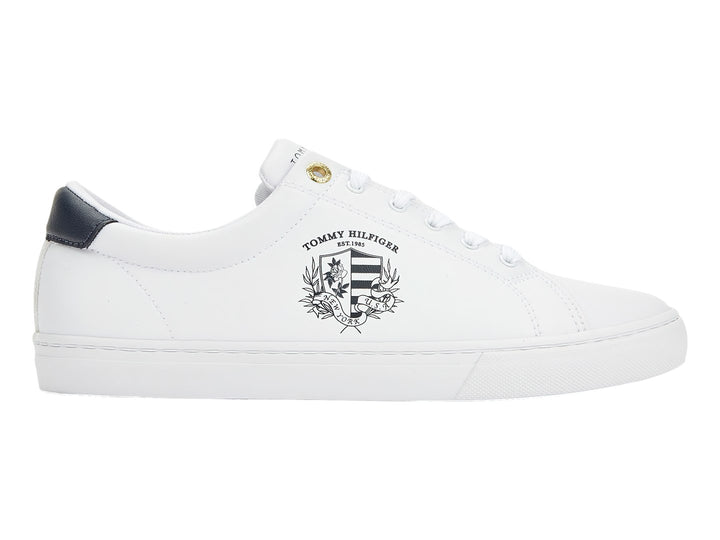 Tenis blancos de mujer marca Tommy Hilfiger con estampado de escudo en el lateral y detalle azul marino en el talón.