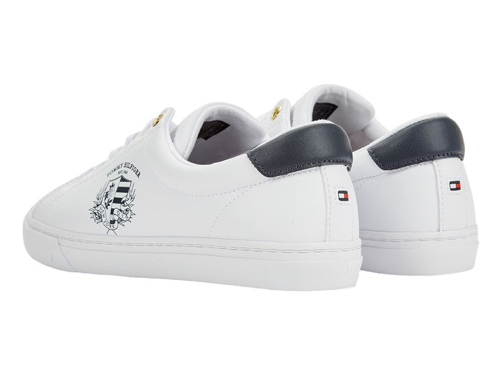 Tenis blancos de mujer marca Tommy Hilfiger con estampado de escudo en el lateral y detalle azul marino en el talón.