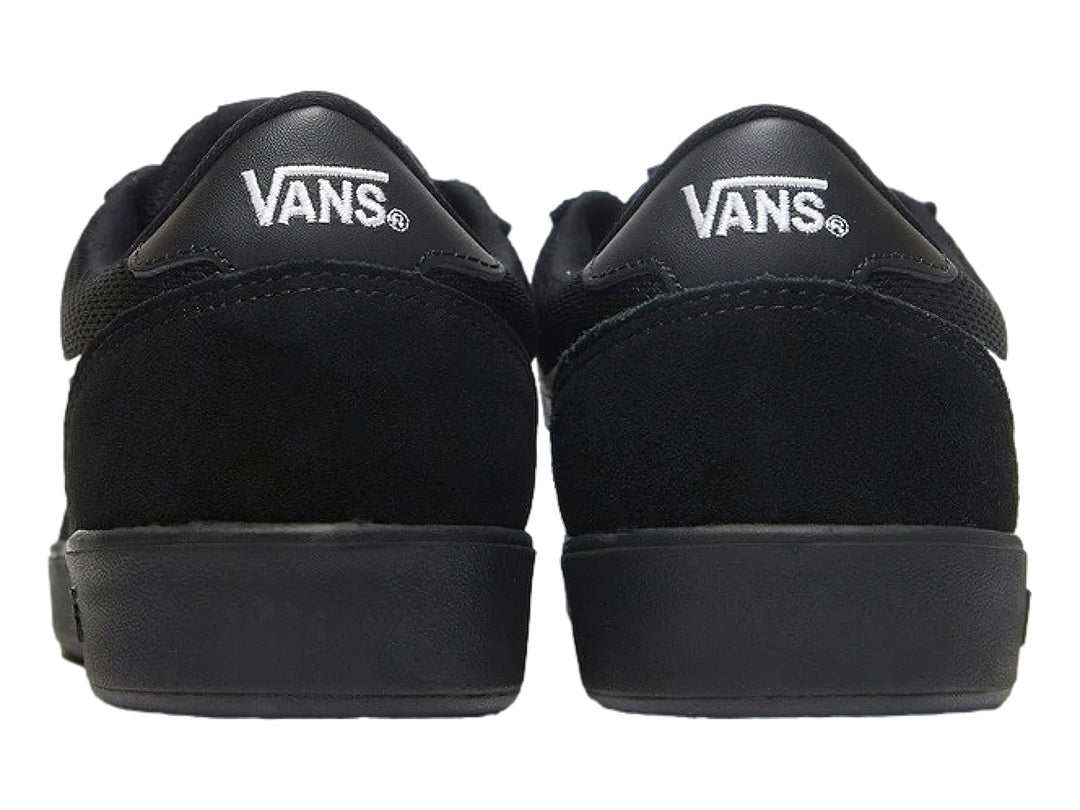 Tenis Vans color negro con franja blanca lateral y suela plana.