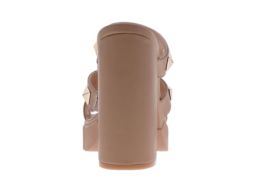 Sandalias beige de plataforma y tacón grueso con correas adornadas con tachuelas doradas cuadradas.