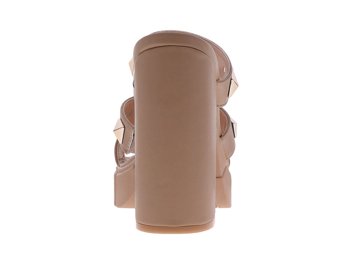 Sandalias beige de plataforma y tacón grueso con correas adornadas con tachuelas doradas cuadradas.