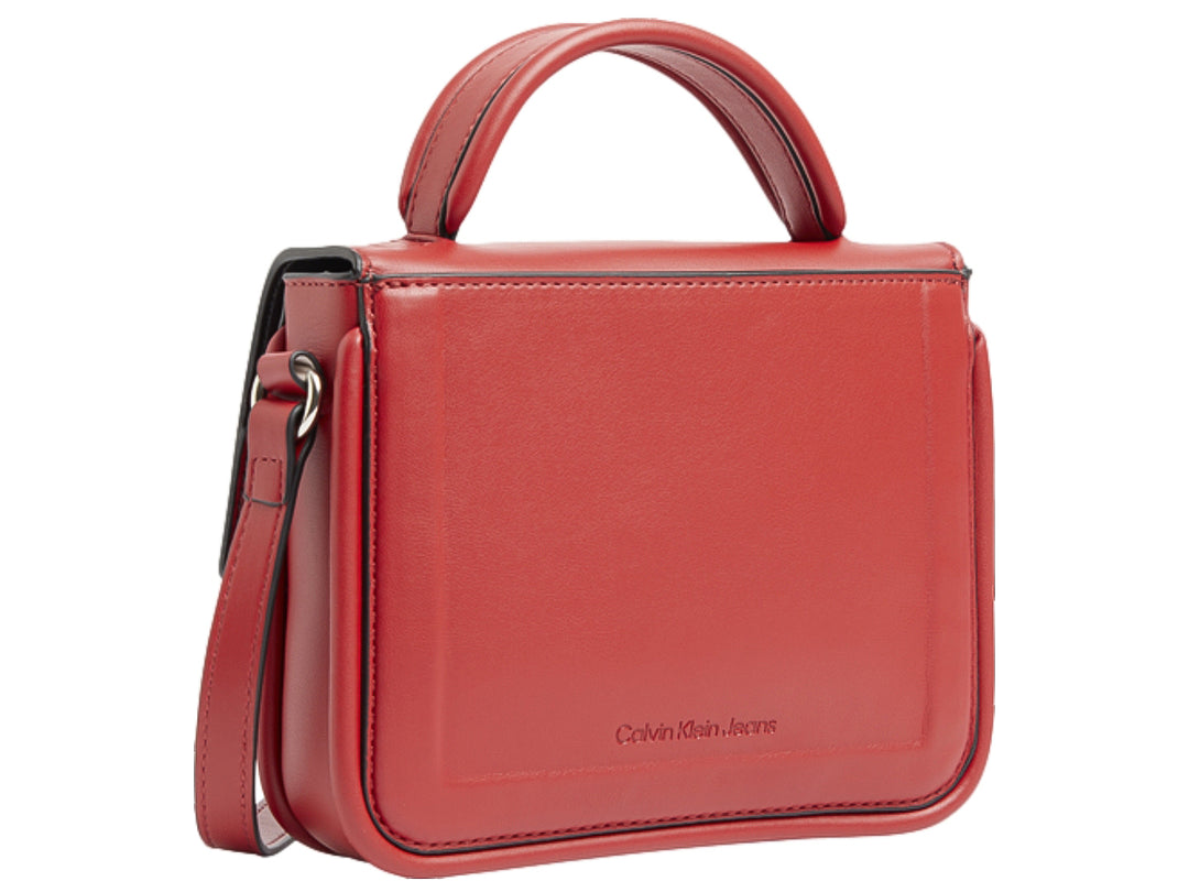 Bolso rojo de Calvin Klein con asa superior, correa ajustable y logo CK grabado en relieve.
