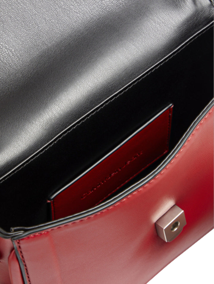 Bolso rojo de Calvin Klein con asa superior, correa ajustable y logo CK grabado en relieve.