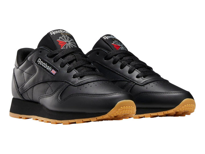 Tenis Reebok Classic Leather en color negro con suela marrón y detalles minimalistas.