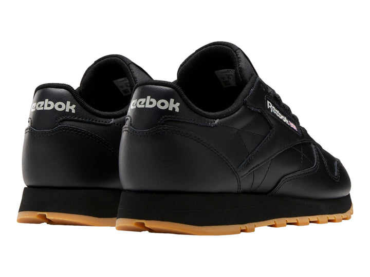 Tenis Reebok Classic Leather en color negro con suela marrón y detalles minimalistas.