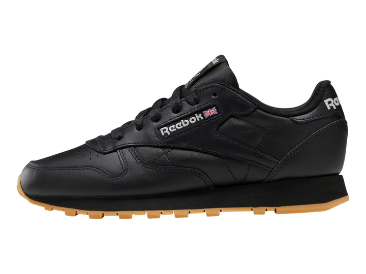 Tenis Reebok Classic Leather en color negro con suela marrón y detalles minimalistas.