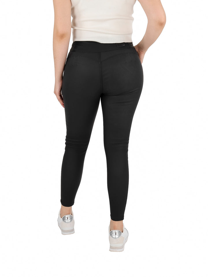 Mujer vistiendo un pantalón negro ajustado de piel sintética y tenis blancos.