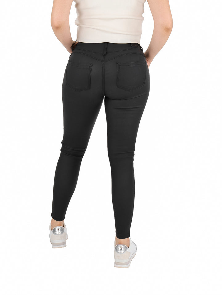 Mujer vistiendo un pantalón ajustado de vinipiel color negro con tenis blancos.