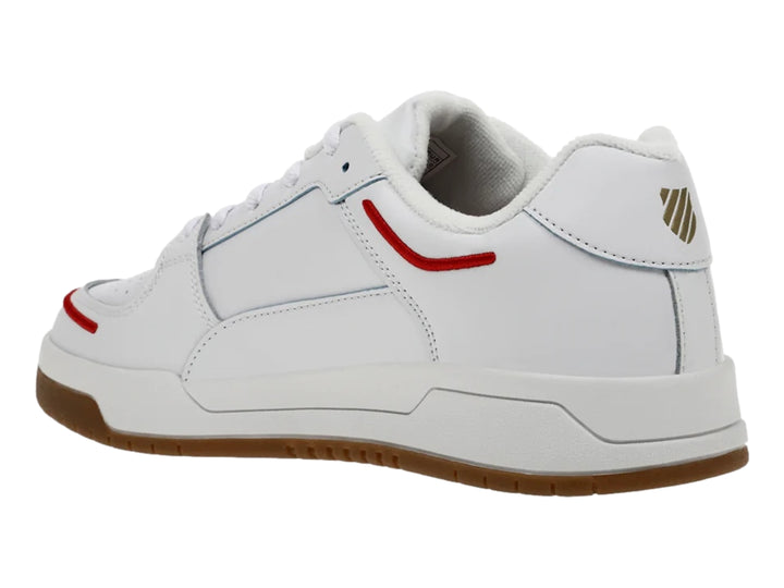 Tenis K-Swiss blancos con suela de goma marrón y detalles decorativos en rojo y negro.