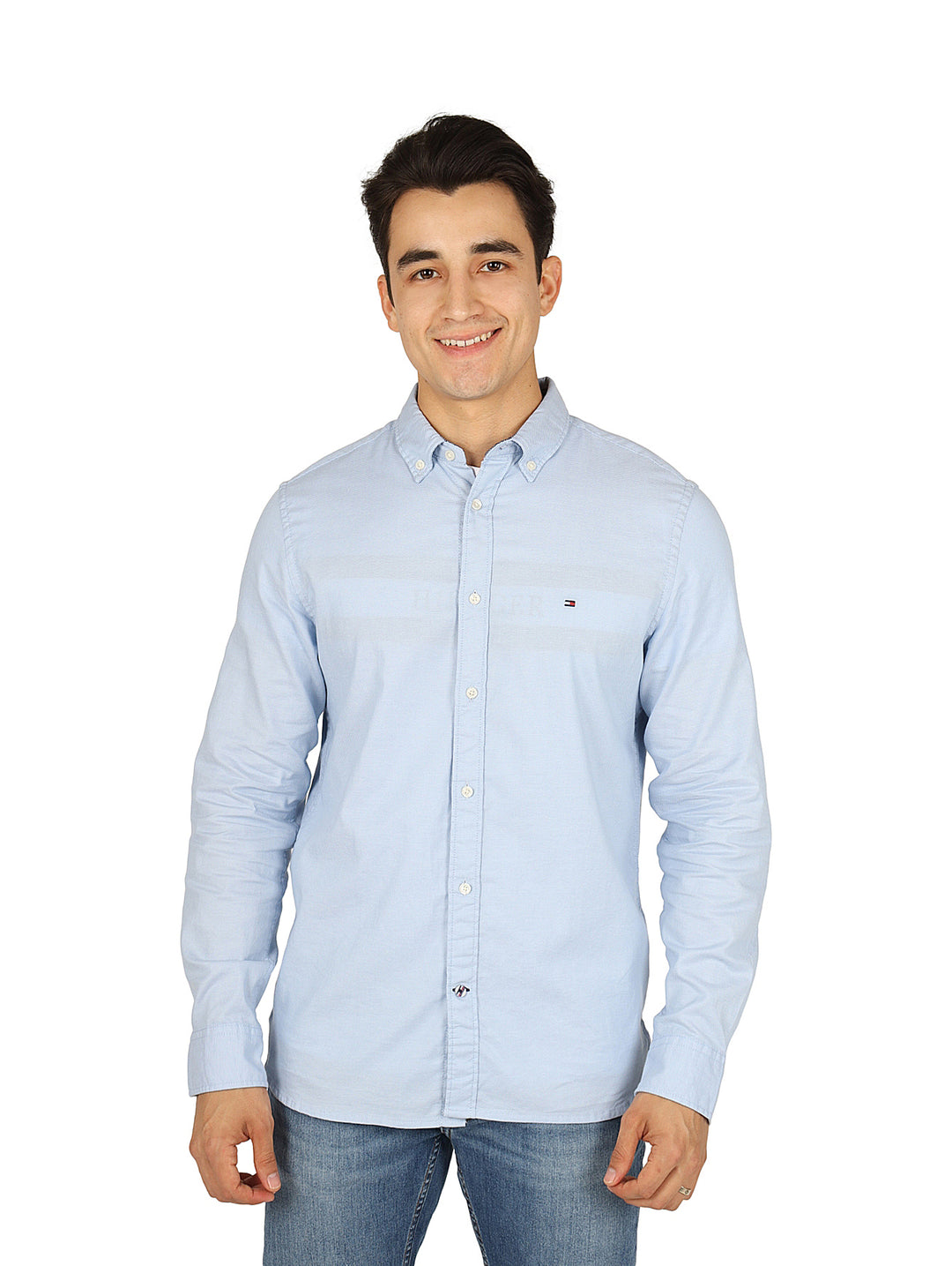 Hombre vistiendo una camisa Tommy Hilfiger de color azul claro con botones y manga larga.