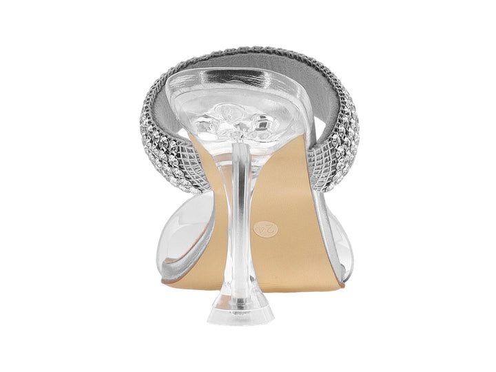 Sandalia de tacón alto color plata con tira frontal transparente y correa decorada con pedrería brillante.