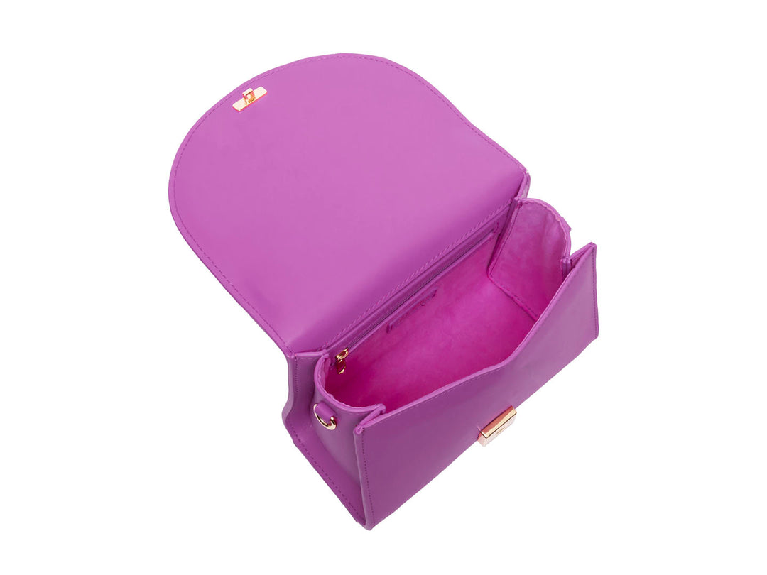 Bolso Steve Madden color rosa con asa circular y detalle de cadena dorada colgante.