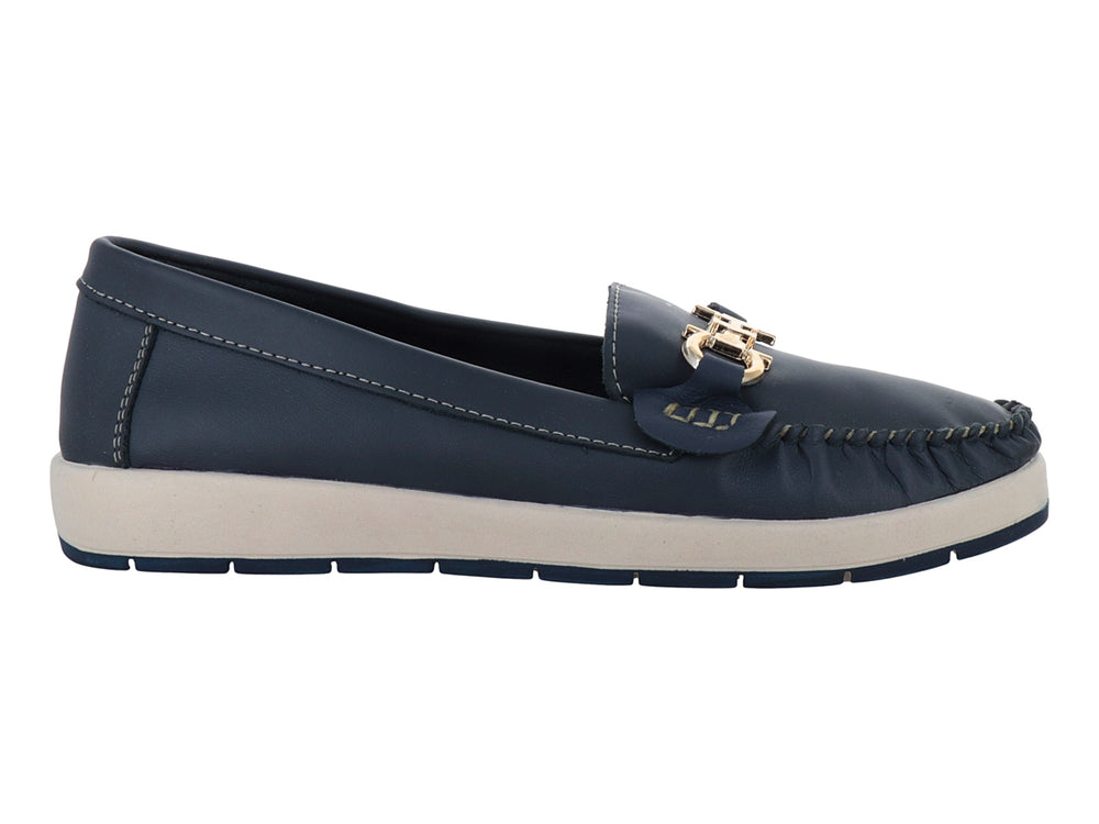 Zapato tipo mocasín azul con suela blanca y detalle metálico dorado en la parte superior.