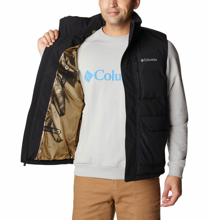 Hombre vistiendo un chaleco negro acolchado de la marca Columbia sobre una camisa gris.