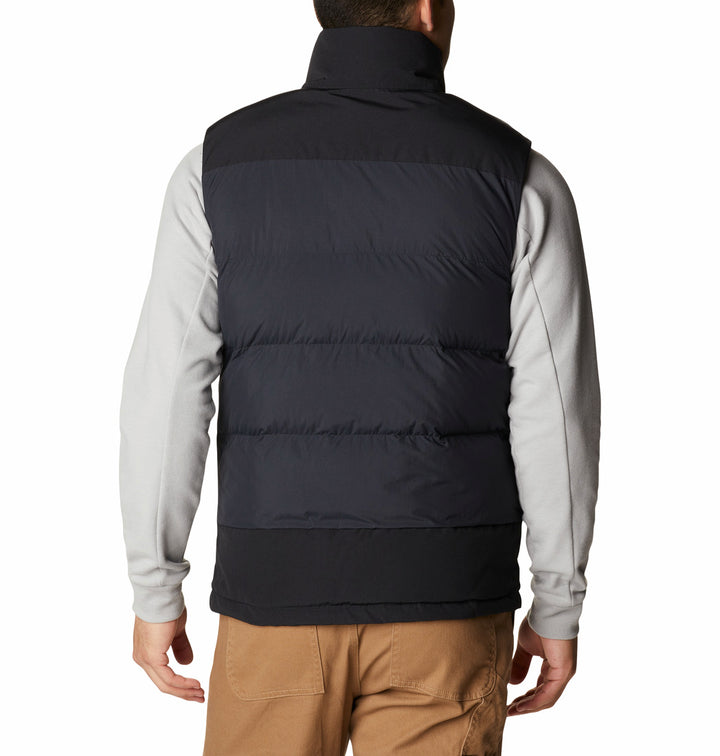 Hombre vistiendo un chaleco negro acolchado de la marca Columbia sobre una camisa gris.