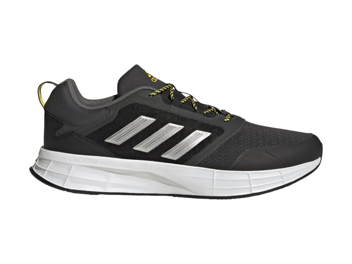 Tenis deportivos Adidas color gris oscuro con franjas plateadas, suela blanca y detalles en amarillo.