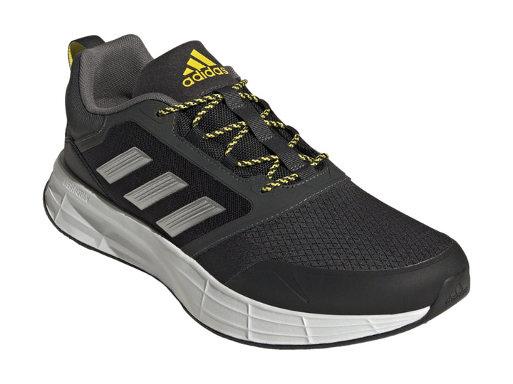 Tenis deportivos Adidas color gris oscuro con franjas plateadas, suela blanca y detalles en amarillo.