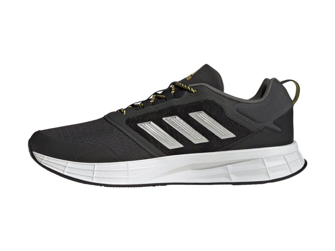 Tenis deportivos Adidas color gris oscuro con franjas plateadas, suela blanca y detalles en amarillo.