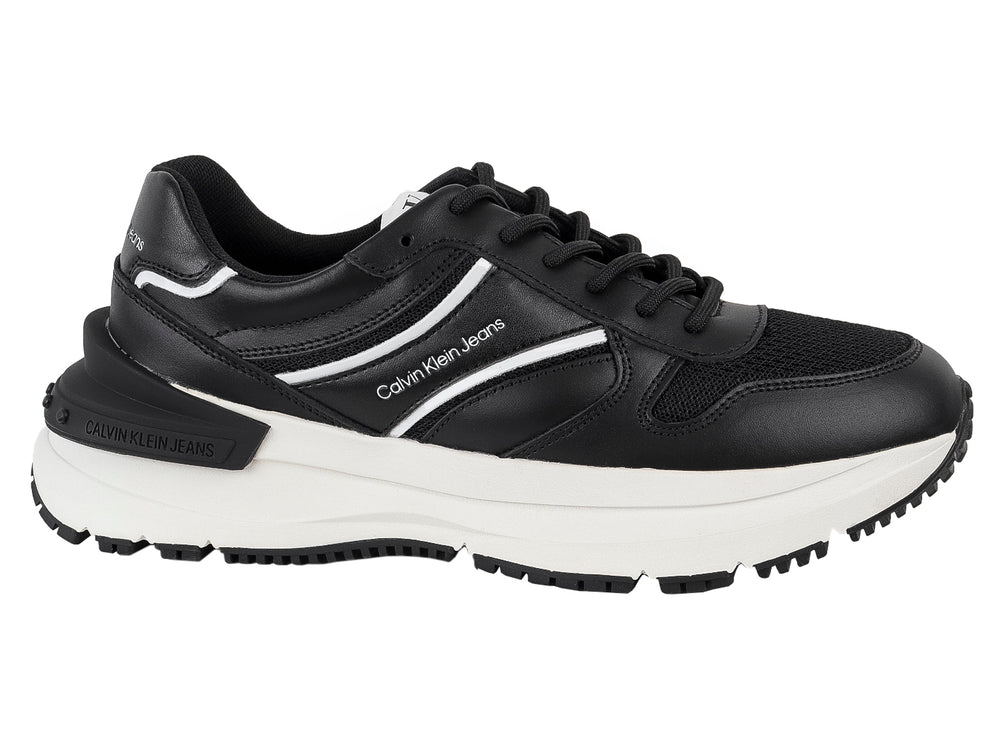 Tenis Calvin Klein Jeans color negro con suela blanca y detalles laterales en blanco.