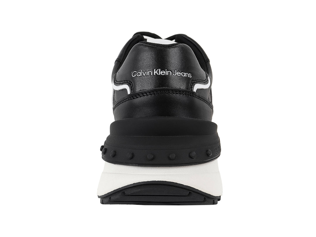 Tenis Calvin Klein Jeans color negro con suela blanca y detalles laterales en blanco.