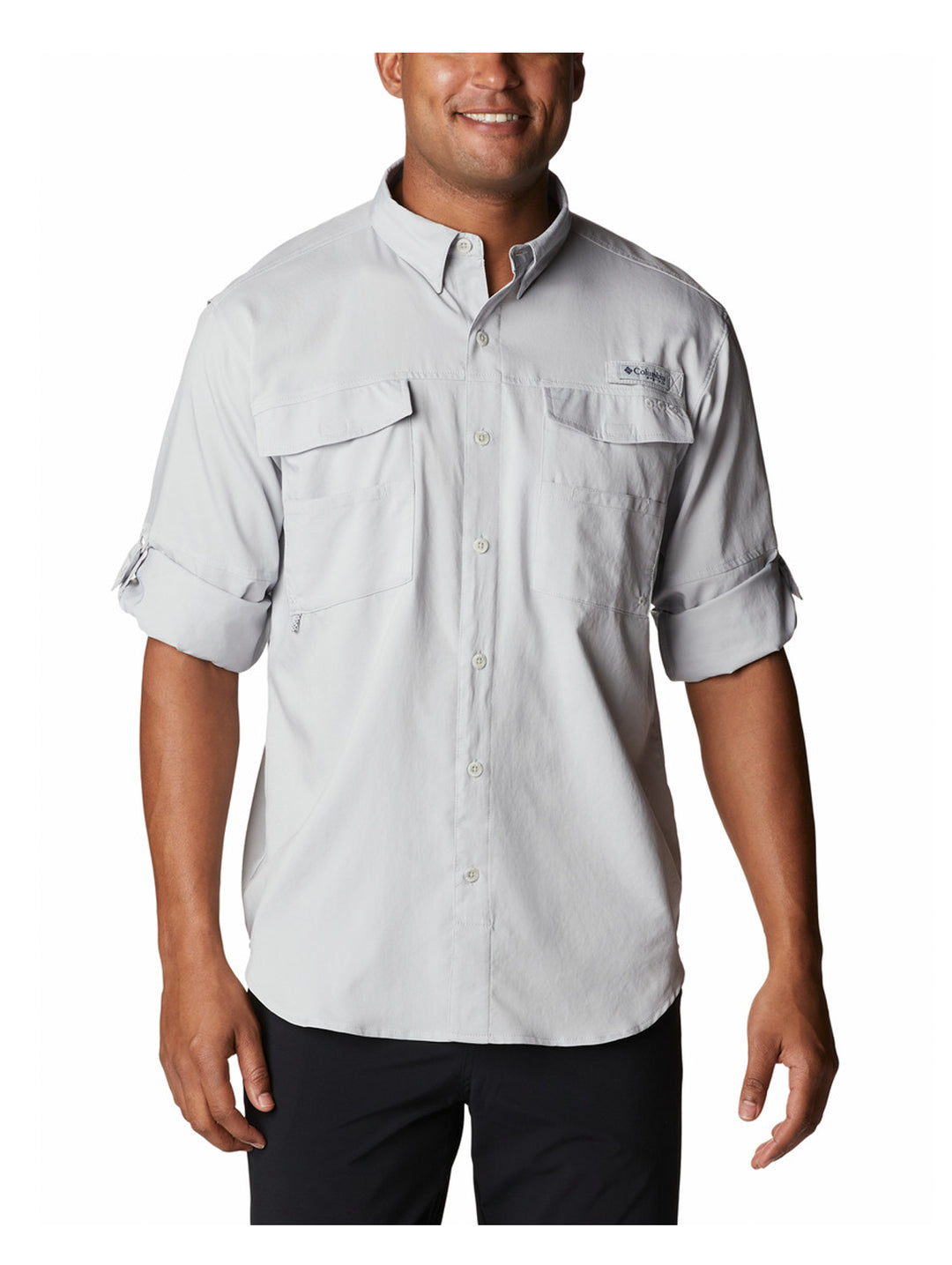 Hombre vistiendo camisa Columbia de color gris claro con mangas remangadas y bolsillos frontales.