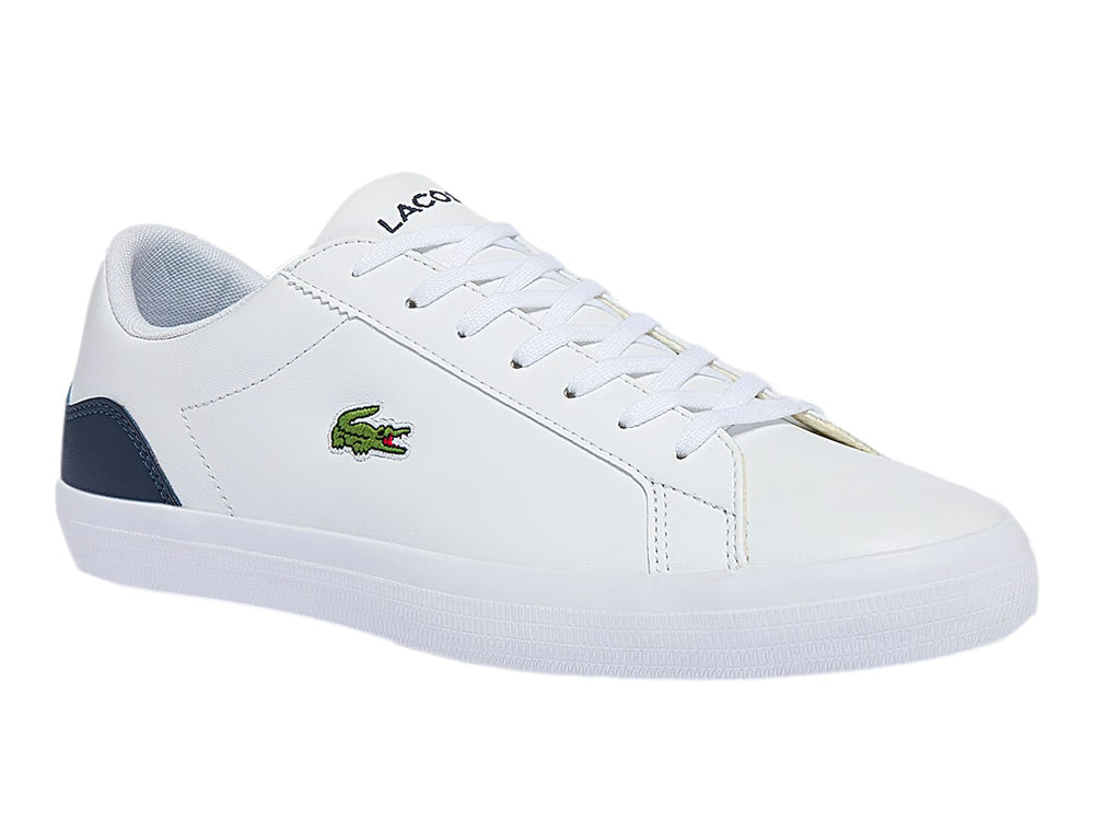 Tenis Lacoste blancos con talón azul marino y logotipo de cocodrilo verde.
