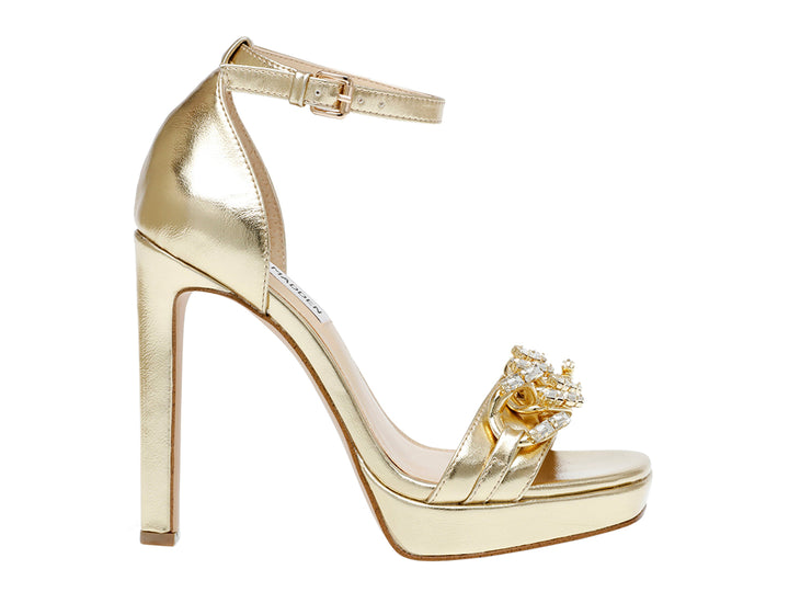 Sandalia dorada de Steve Madden con tacón alto, plataforma y detalles de pedrería en la parte frontal.