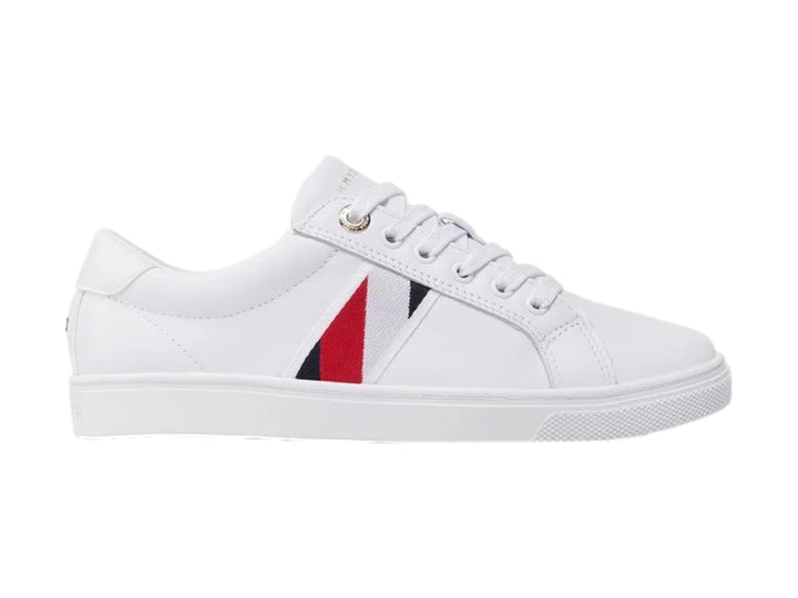 Tenis blancos Tommy Hilfiger de corte bajo con franja lateral en rojo y azul y suela blanca.
