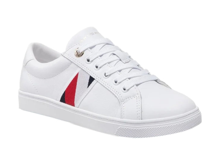 Tenis blancos Tommy Hilfiger de corte bajo con franja lateral en rojo y azul y suela blanca.