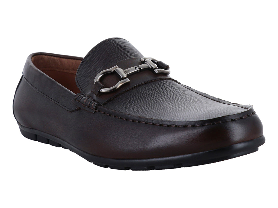 Zapato mocasín de cuero marrón con detalle de herraje metálico plateado en la parte superior.